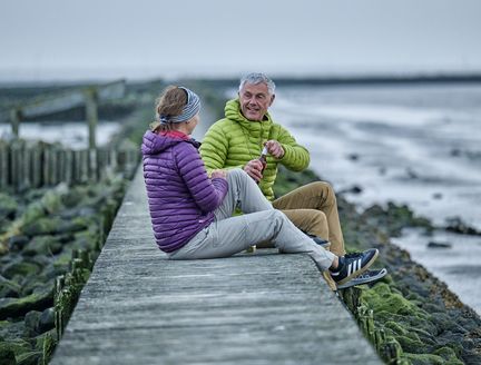 Paar genießt ein Getränk mit Blick auf das Wattenmeer.