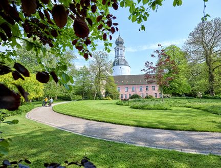 Grüner Schlosspark mit Blick auf ein kleines Schloss