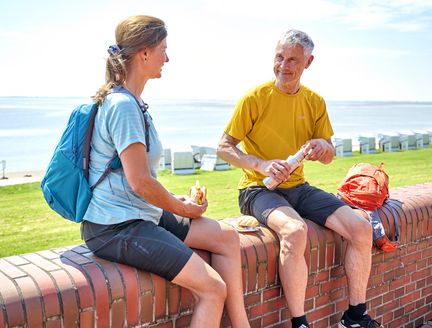 Radfahrende machen mit Fischbrötchen Pause an der Wilhelmshavener Promenade