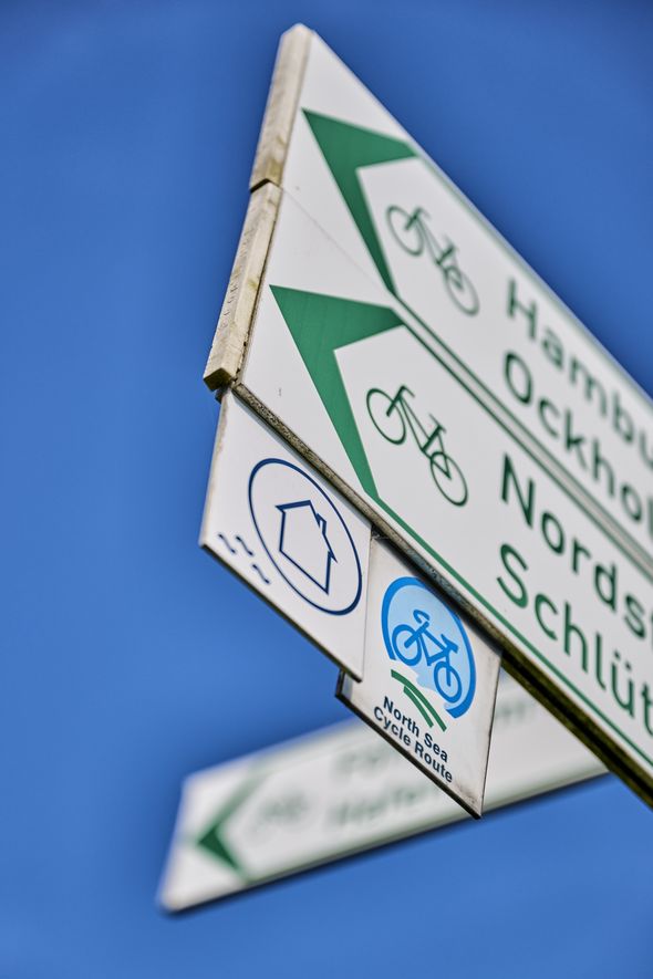 Wegweiser mit Routenlogo des Nordseeküsten-Radwegs